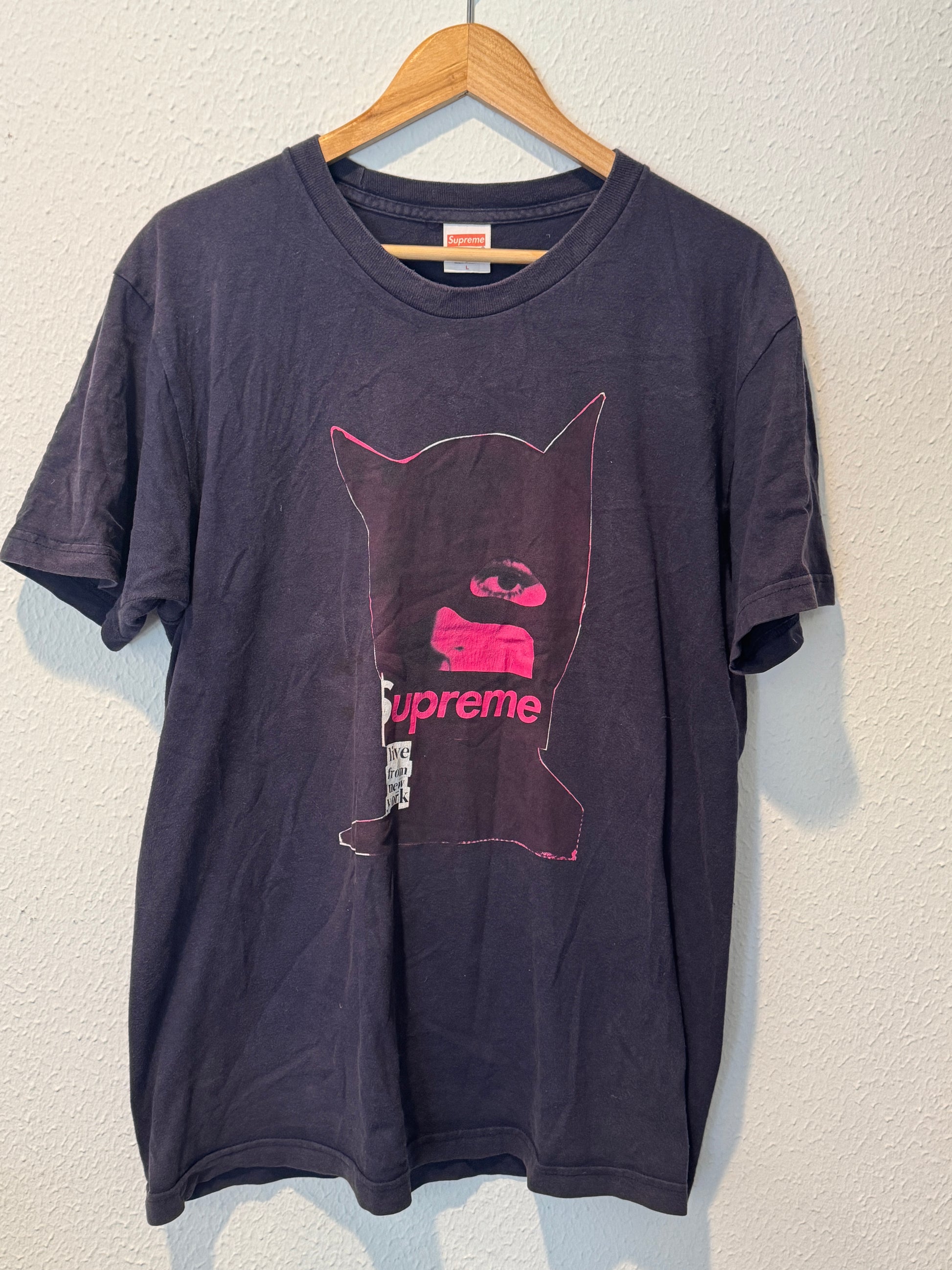 Folded black t-shirt with pink graphic on a white background
