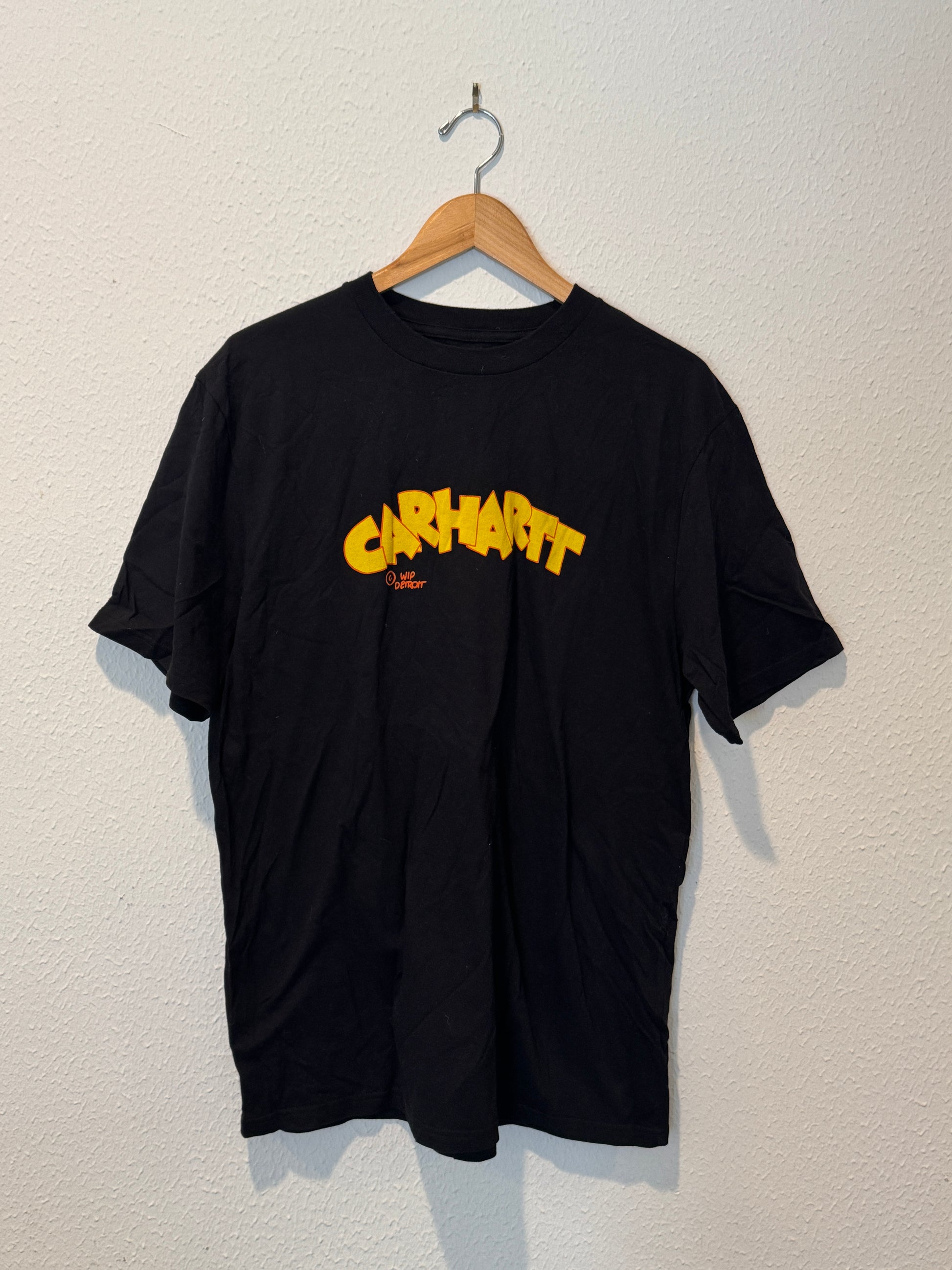 Black hoodie with yellow text on a beige background