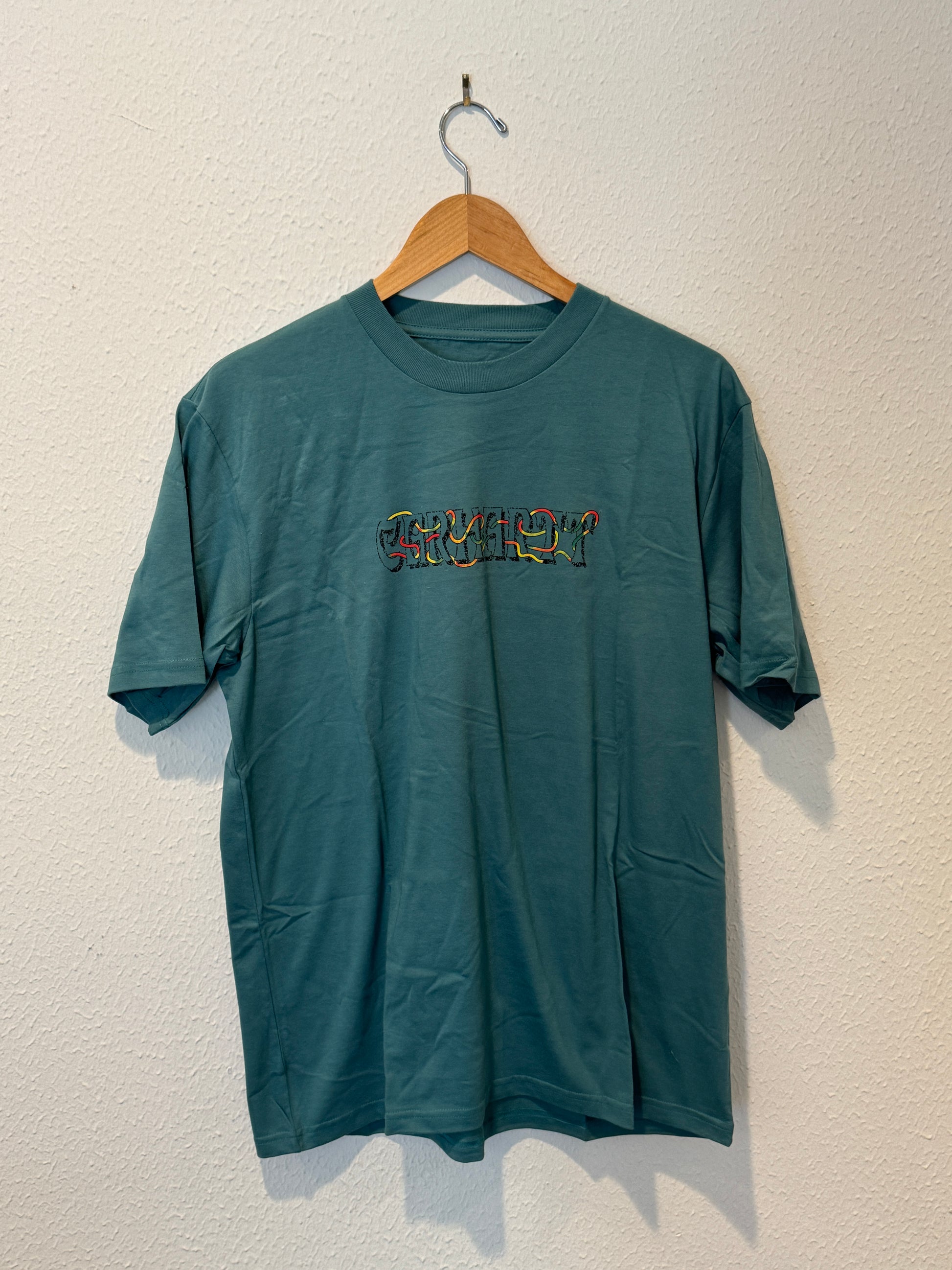 Green t-shirt with embroidery on a wooden hanger against a white background