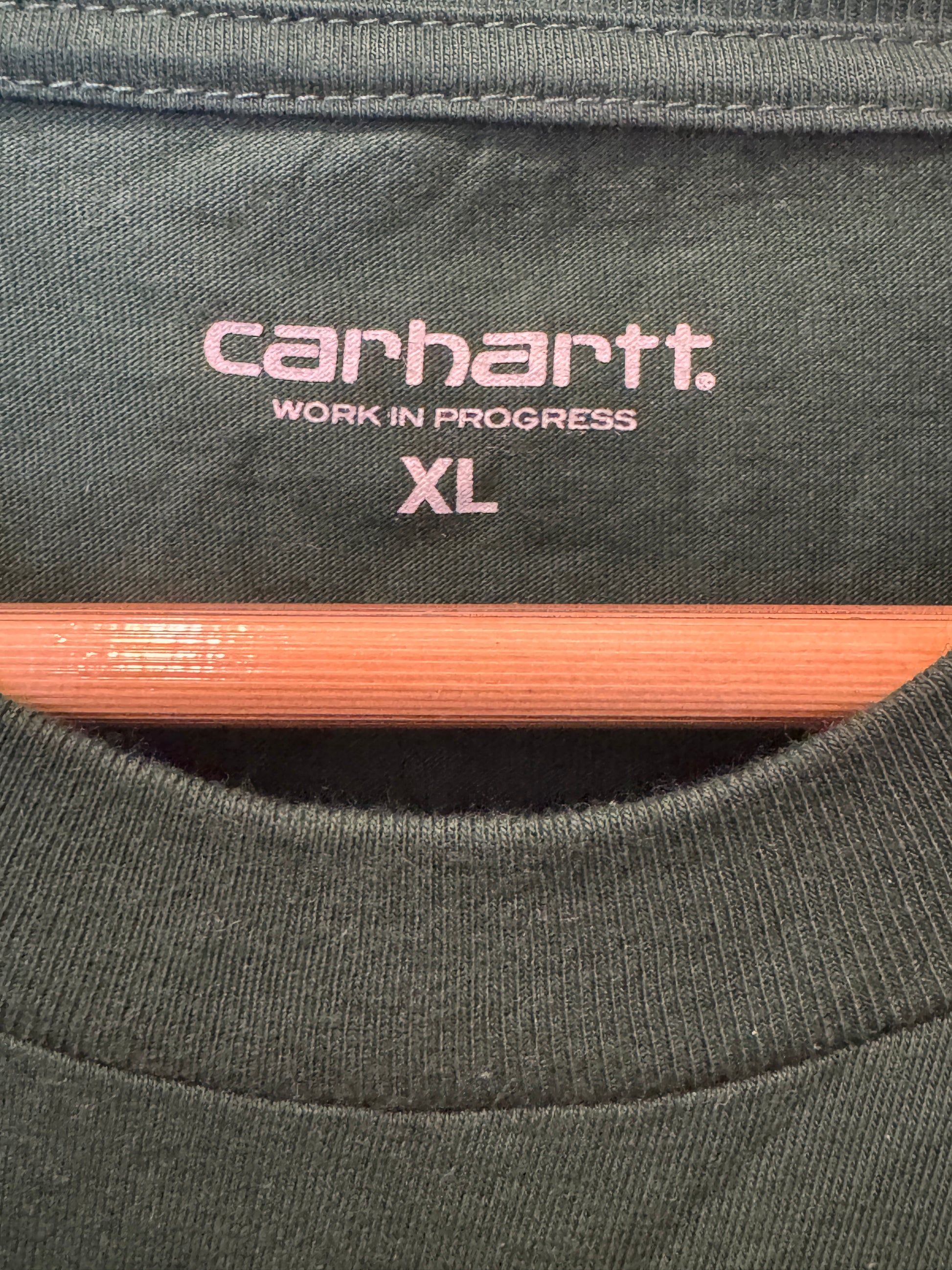 Close-up of a Carhartt label on a piece of fabric with a wooden stick.