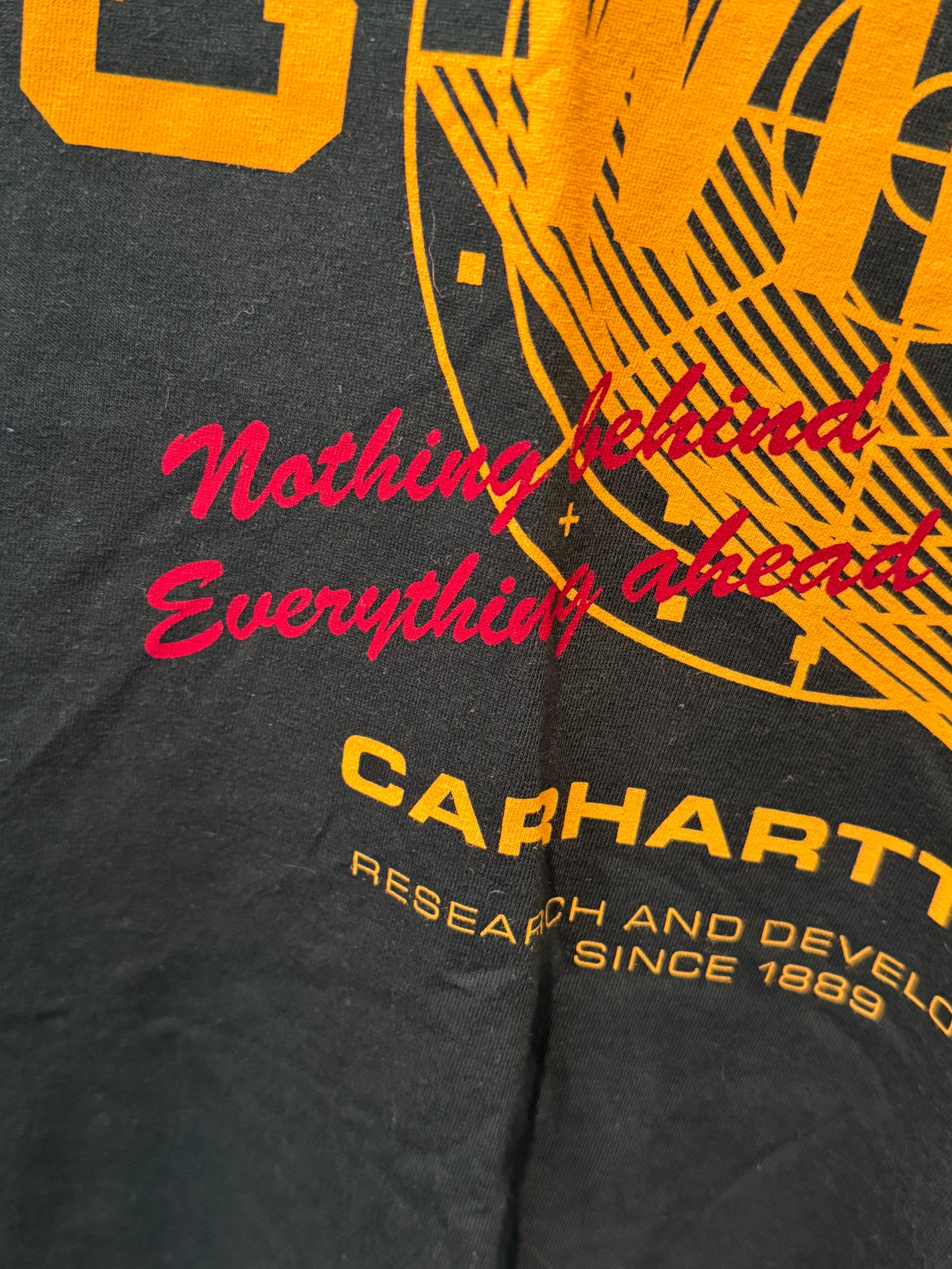 Black jacket with red and yellow text and graphics, featuring the Carhartt brand.