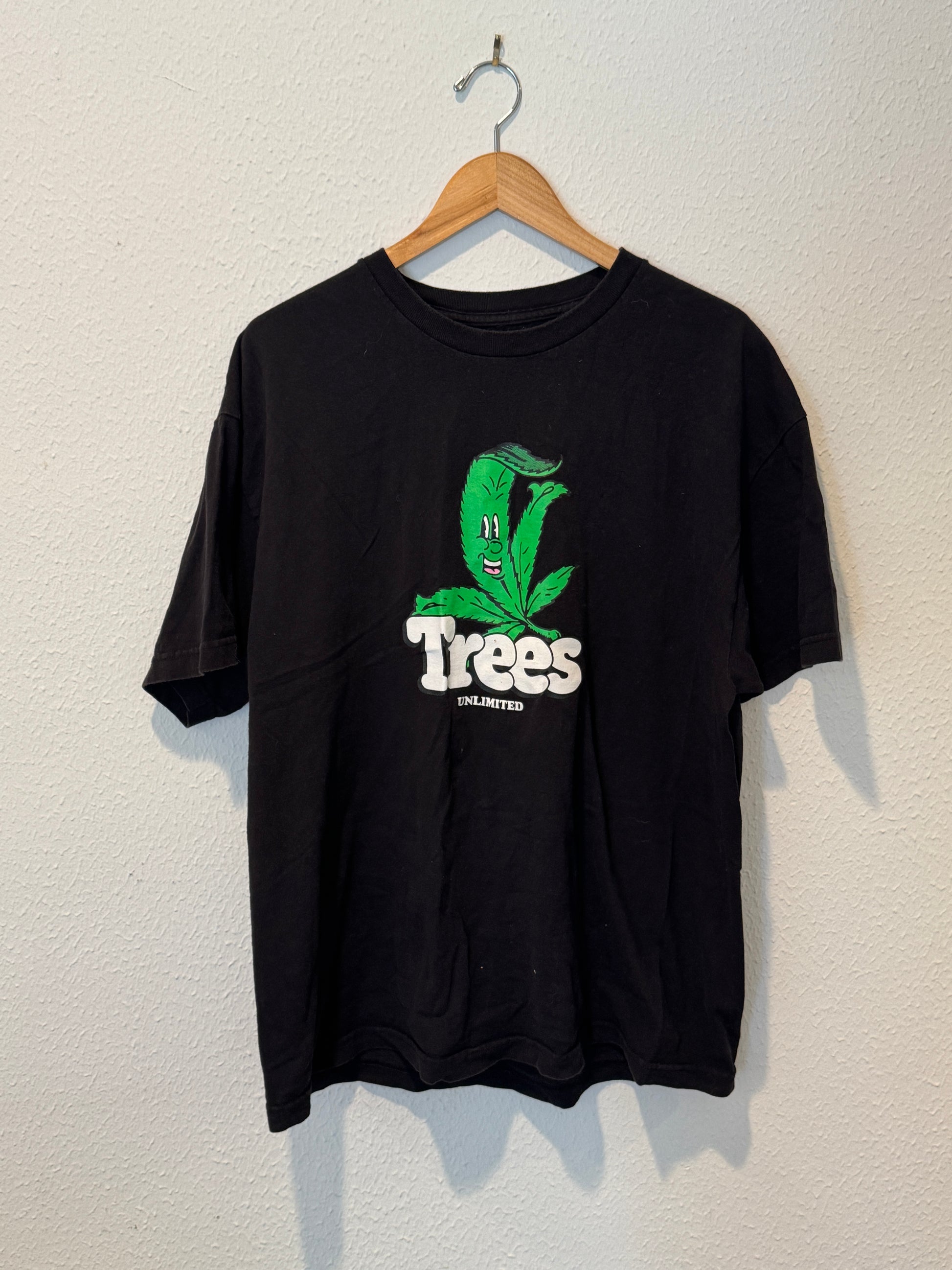 Black t-shirt with green and white graphic on a hanger against a light background